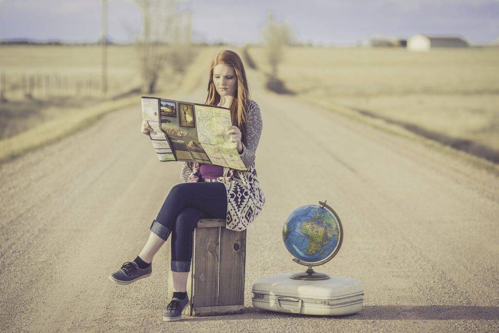 Girl sitting beside the road with her luggage deciding what dreams she should chase next.