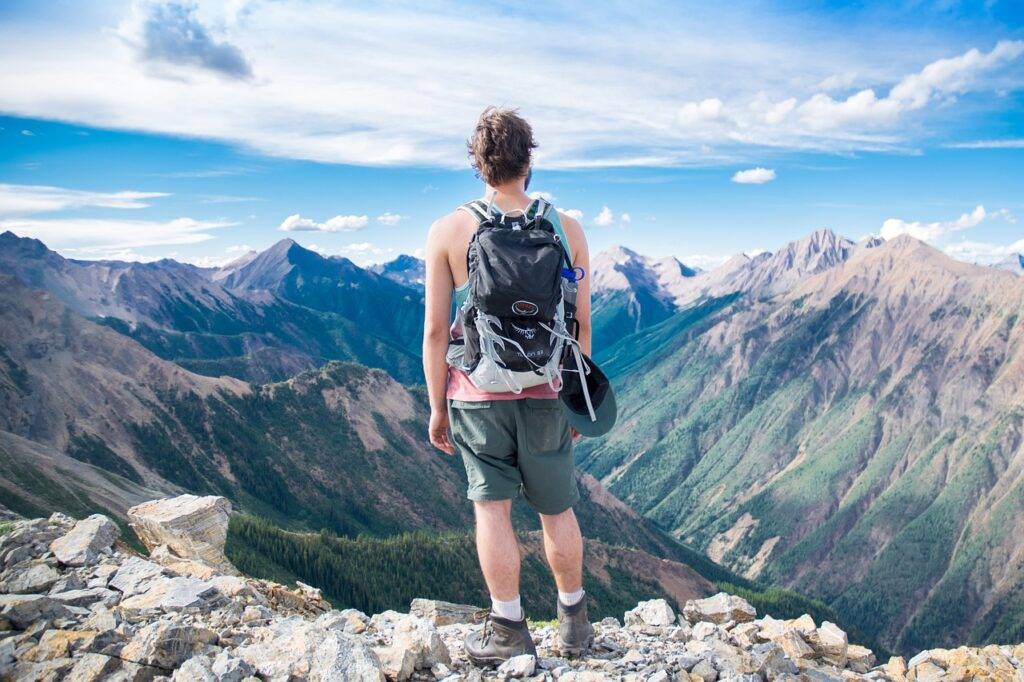 Man high up in the mountains overlooking a valley on a clear day finally reaching a dream he has wanted.