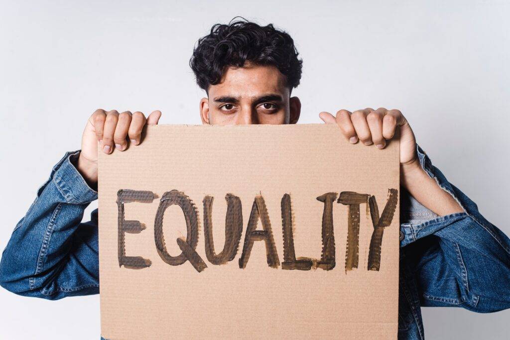 Man holding up a cardboard sign that reads "Equality".