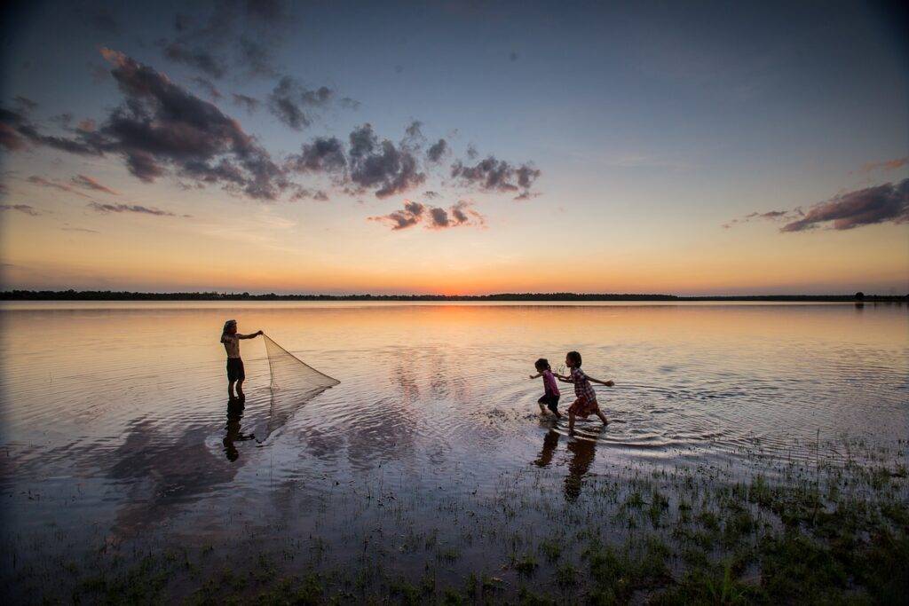 Innocent children playing in the lake during sunset.