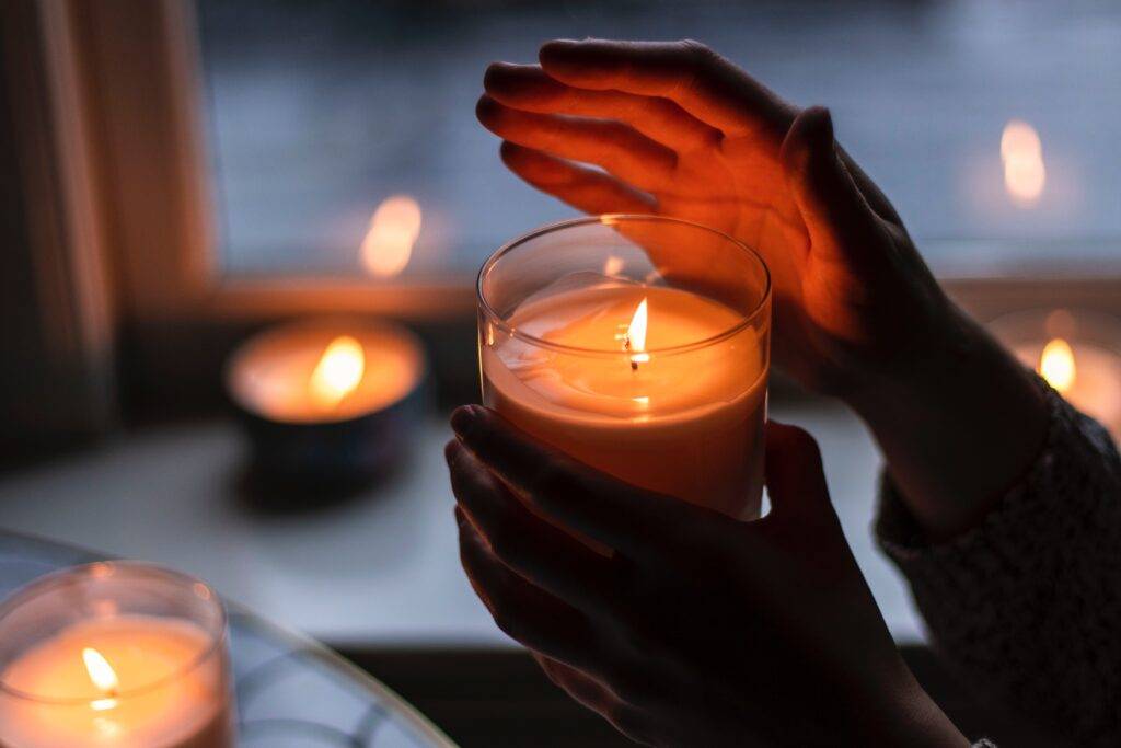 A small candle being held up and protected by hands to light up the darkness.