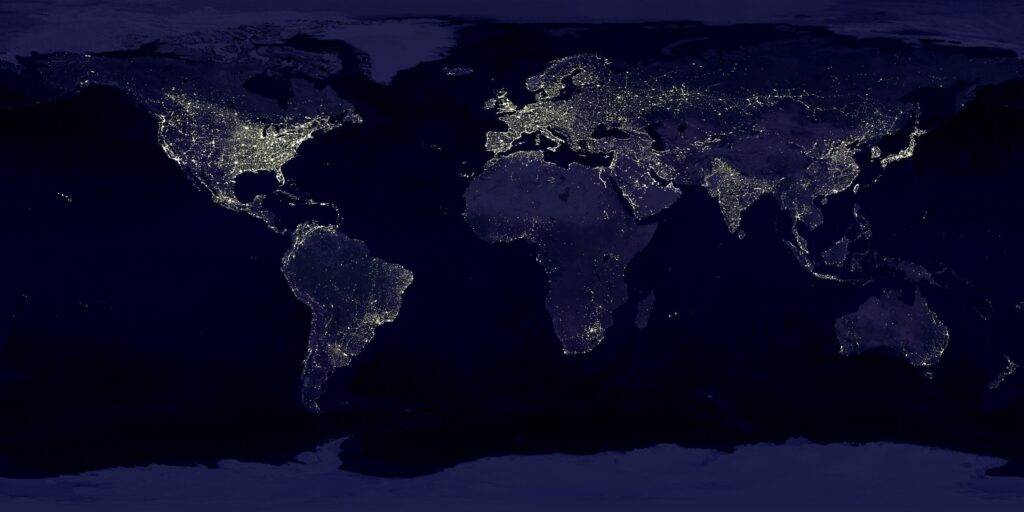 A map of the continents of the world lit up at night with lights.