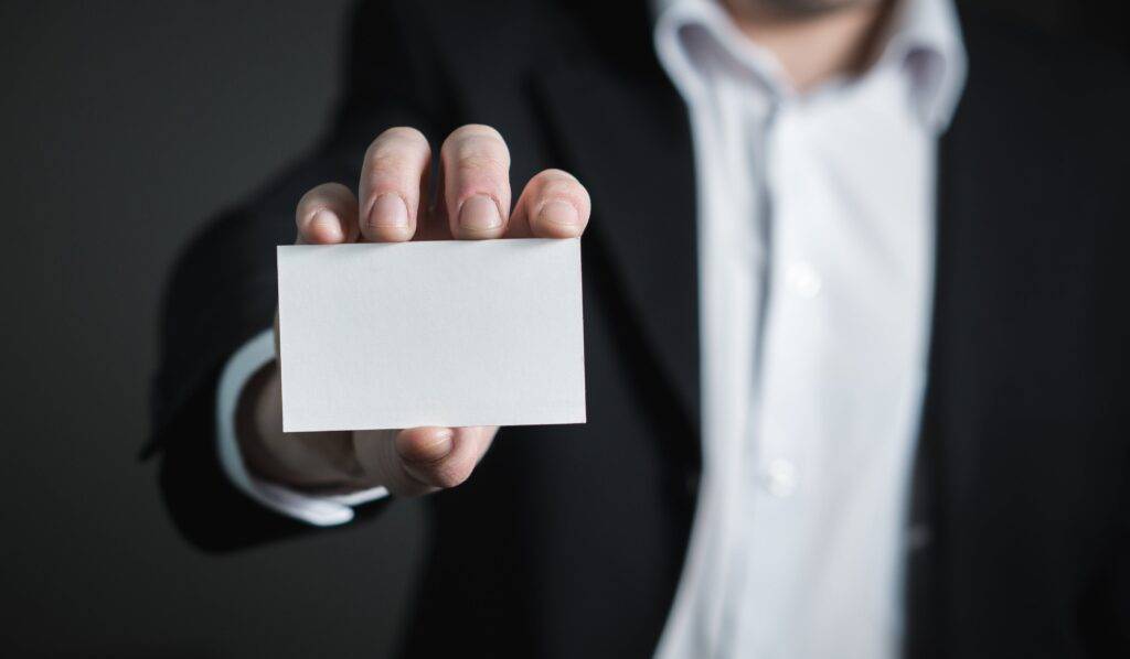 Business man holding a blank notecard representing the societal conditioning of our culture towards our vulnerability.